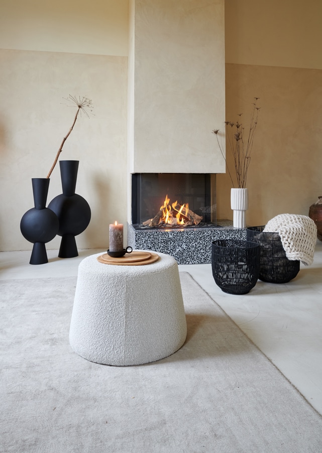 Naturel woonkamer met witte boucle poef en zwarte vazen