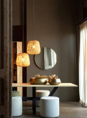 Eettafel Met Poefjes En Rotan Lampen En Gouden Ronde Spiegel Aan De Muur