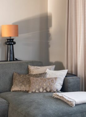 Goud groene Claudi sierkussens op groen grijze bank