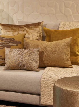 Claudi Sierkussens Met Geel En Gouden Tinten Op Een Beige Bank Met Een Plaid