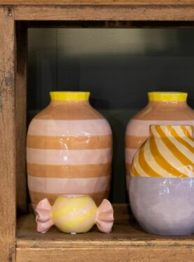 Geel roze snoepjes kandelaar met bijpassende roze oranje paars gestreepte vazen in kast