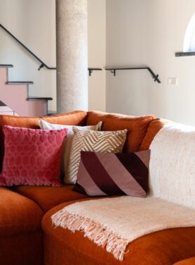 Roestbruine bank met roze en bordeaux rode kussens