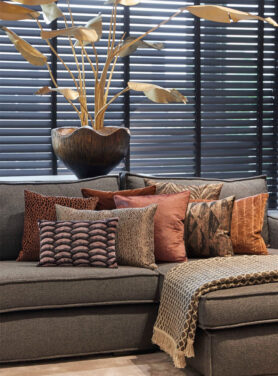 Kussen Met Bruine En Rode Tinten Op Een Grijze Bank En Een Plaid