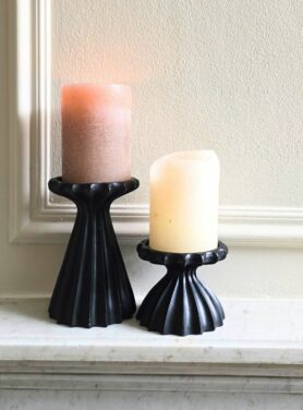 Zwarte kandelaars voor stompkaars op marmeren schouw