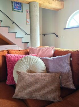 Sierkussens in rode, roze en paarse tinten op roestbruine hoekbank