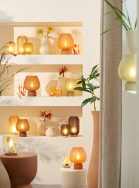 Glazen tafellampjes wit, oranje en bruin in open kast