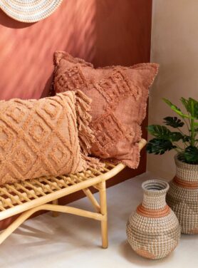sierkussens met franjes terracotta en koraal op houten bankje