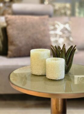 Gele waxinelichthouder van glas op salontafel met groen glazen blad