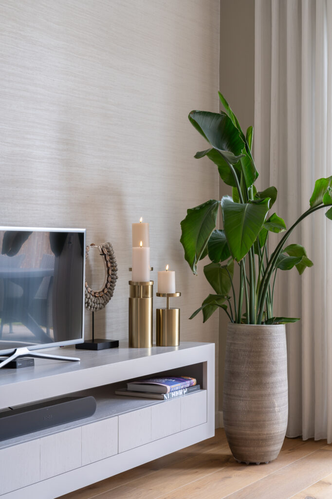tv meubel met gouden kandelaren en een schelpenketting